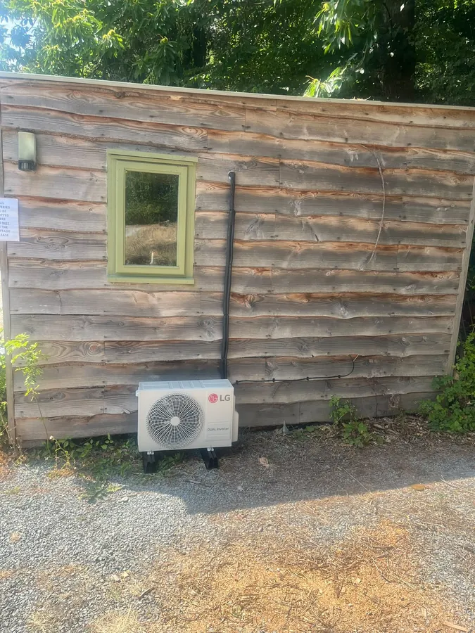 LG outdoor condenser installed beside a timber outbuilding
