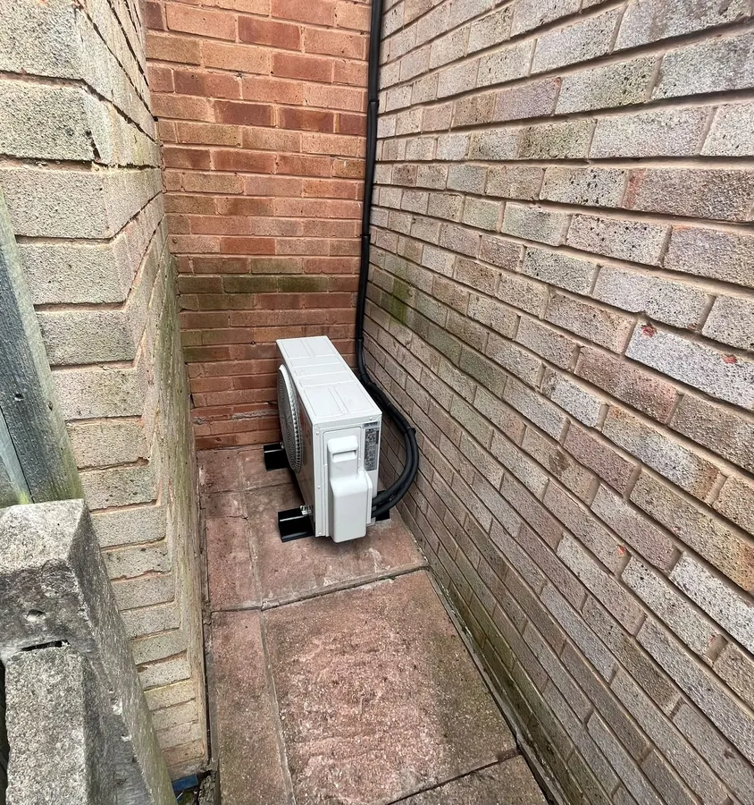 Outdoor air con unit fitted in a narrow brick-walled passage