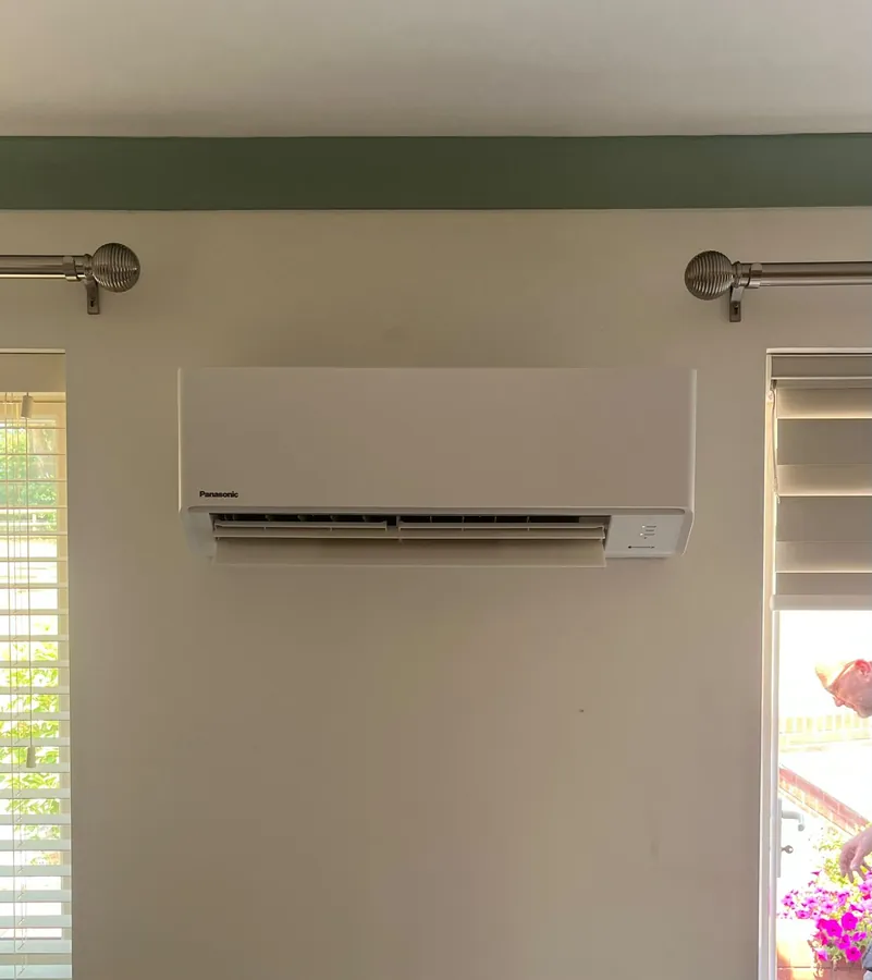 Panasonic split system air conditioner installed between two windows