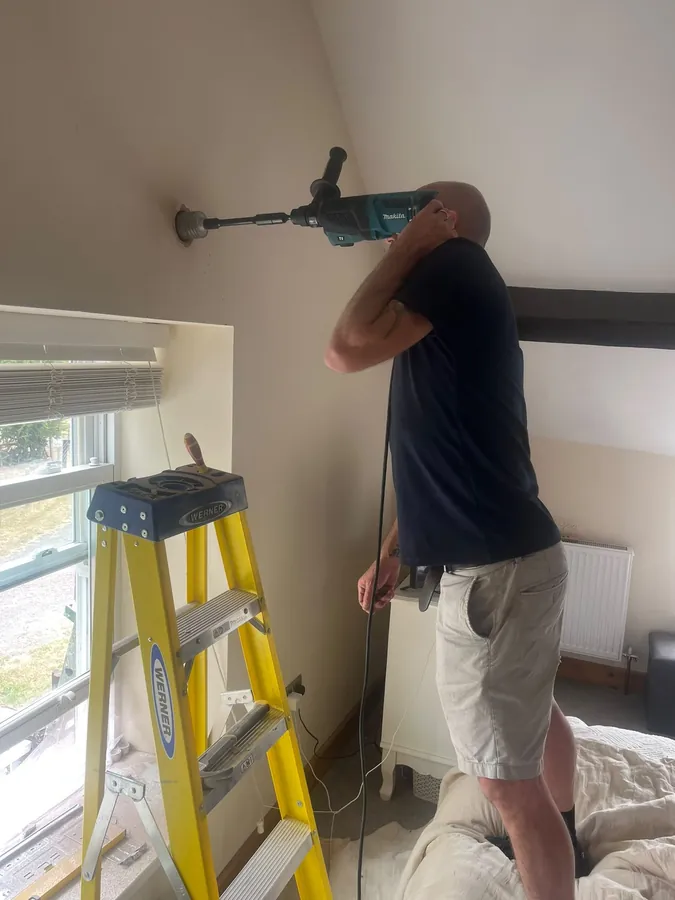Engineer core drilling a wall for air conditioning pipework during a home installation