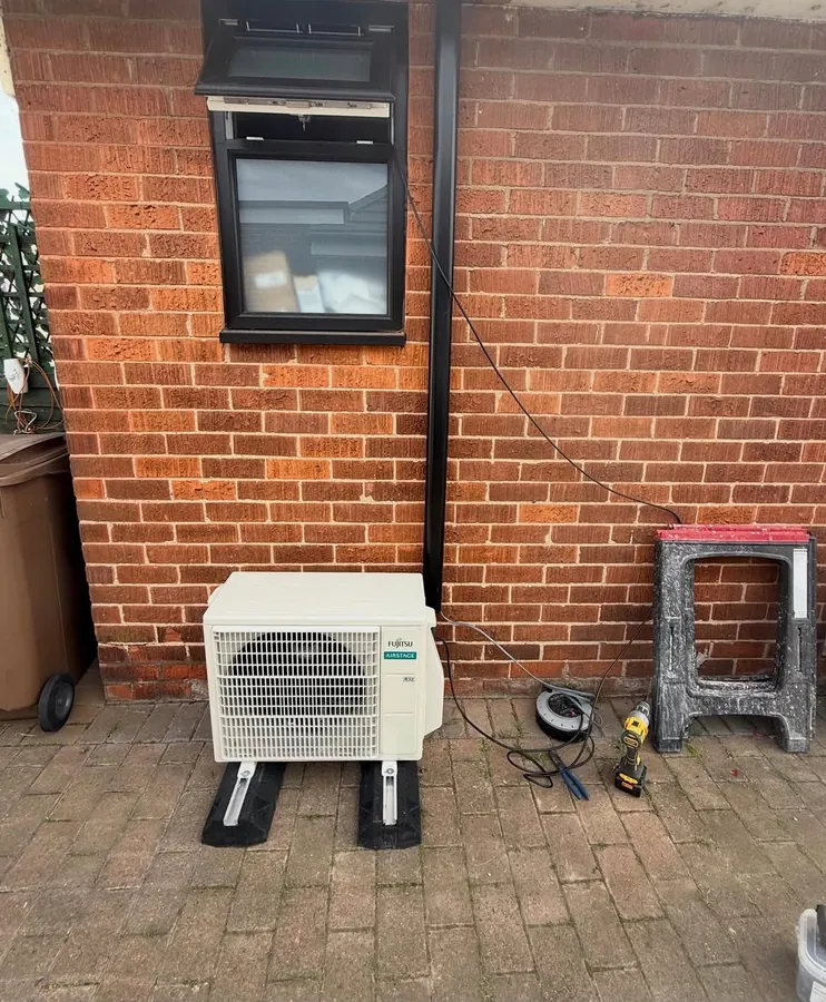 Fujitsu outdoor air conditioning unit installed against a brick wall