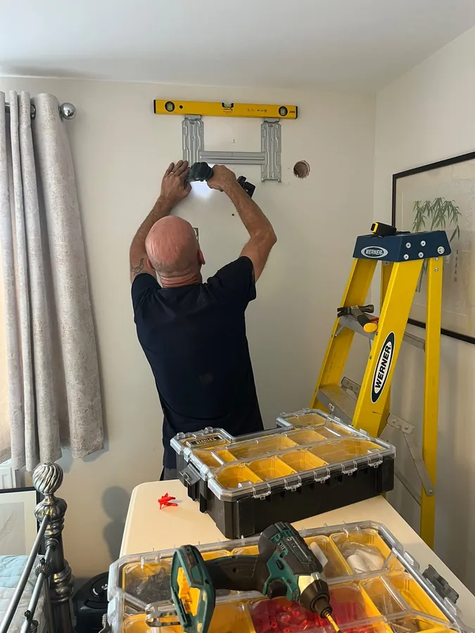 Engineer drilling and levelling a wall bracket for an indoor air con unit