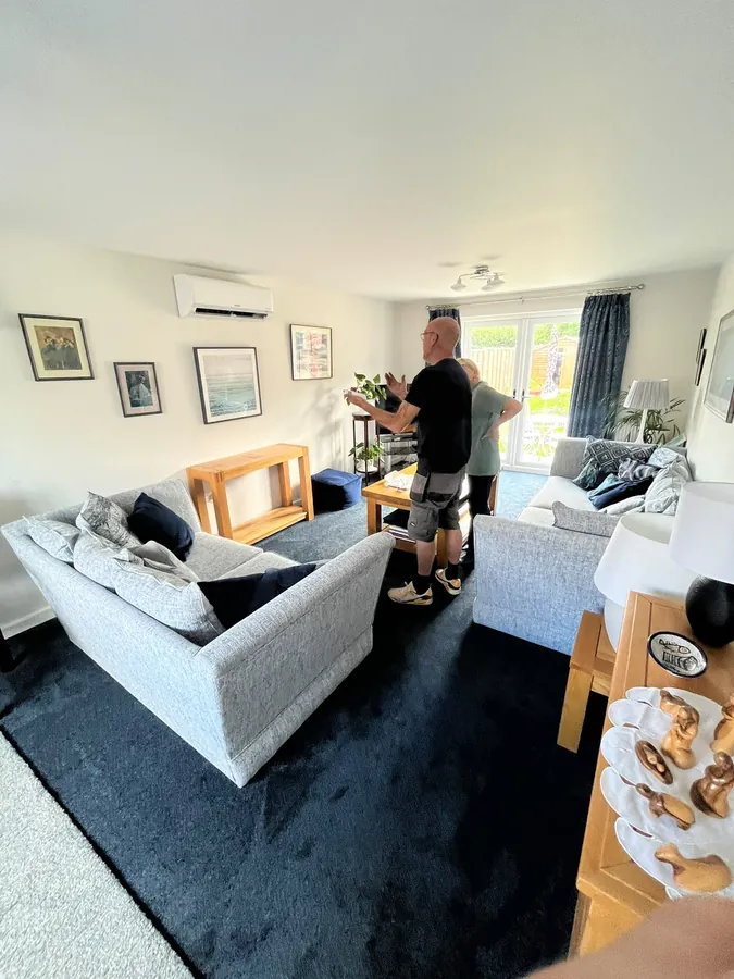 Engineer explaining a newly installed wall-mounted air conditioner to a homeowner in Hereford
