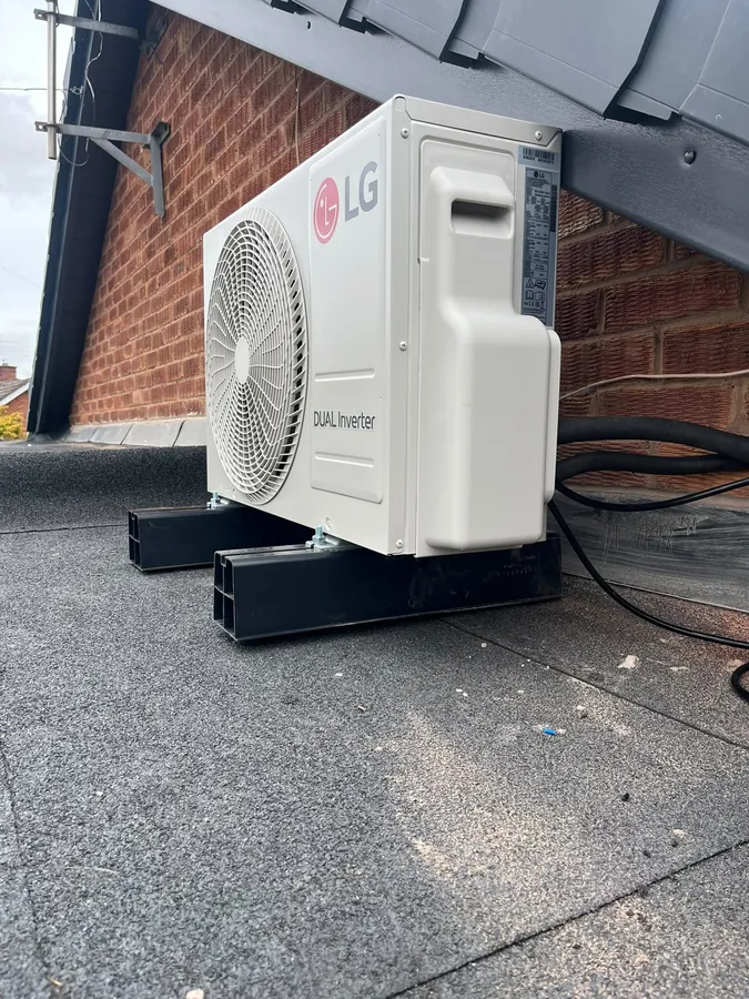 LG outdoor air conditioning unit mounted on stands near a roofline